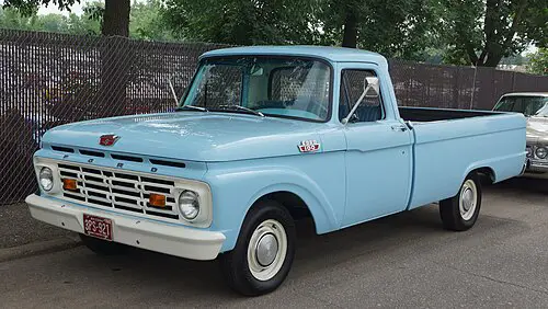 Light blue 1963 Ford F-100 pickup truck parked outdoors, showcasing the early use of FE-series engines in Ford trucks.