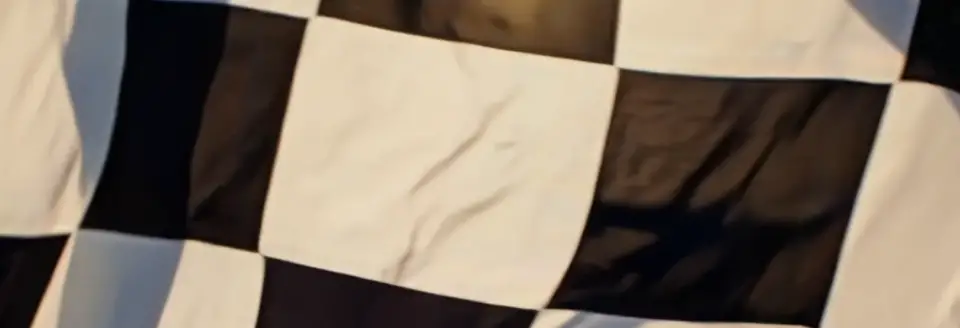 Close-up of a black-and-white checkered racing flag representing victory and endurance racing heritage.